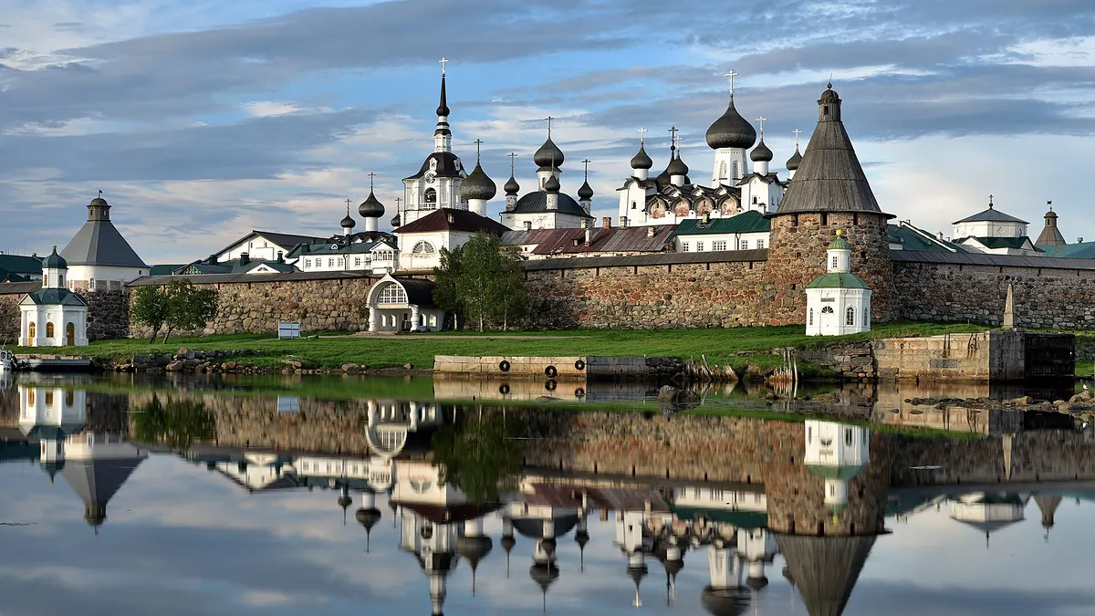 Соловецкий монастырь: стена из валунов, башня и купола соборов отражаются в воде