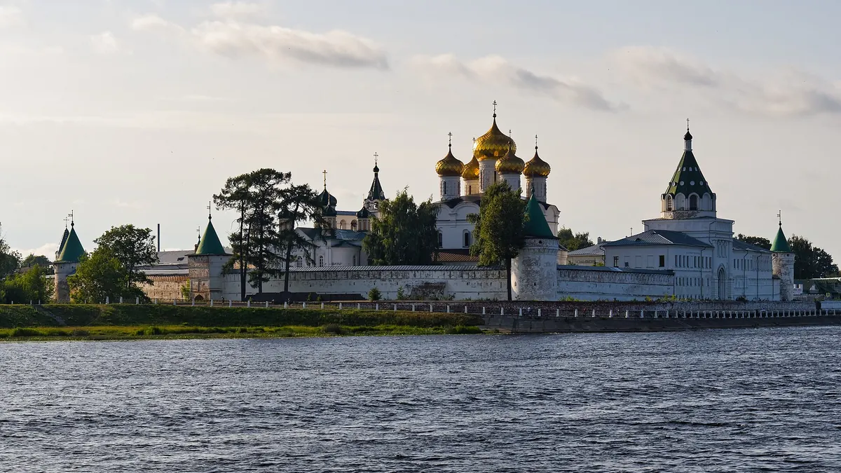 Белые стены, башни и золотые купола Ипатьевского монастыря над рекой в Костроме